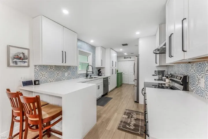 Kitchen featuring stainless steel appliances, a breakfast bar, white cabinetry, and recessed lighting
