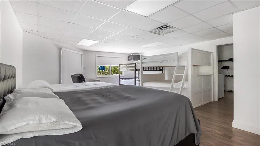 Bedroom with visible vents, a drop ceiling, and wood finished floors