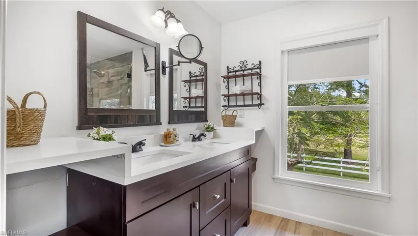 Full bath with a tile shower, baseboards, a sink, and wood finished floors