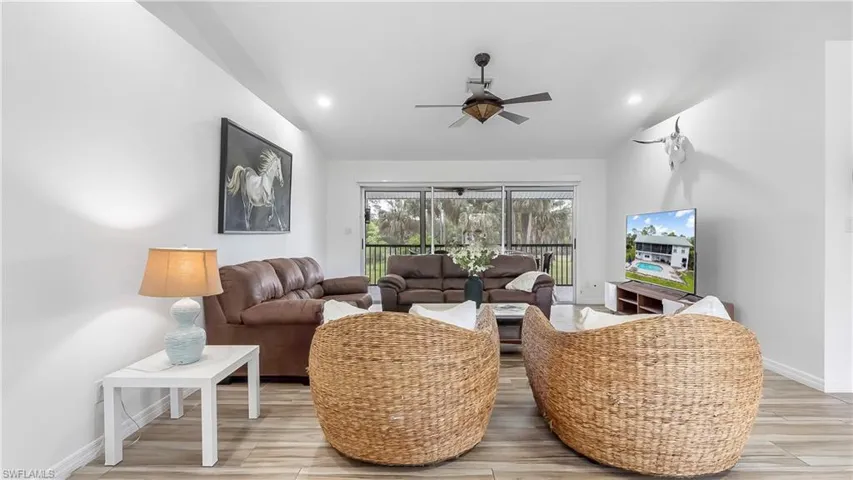 Living room with light wood finished floors, lofted ceiling, baseboards, and ceiling fan