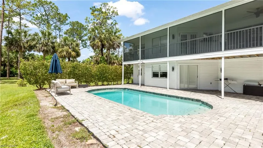 Pool featuring a patio area, a sunroom, and a lawn