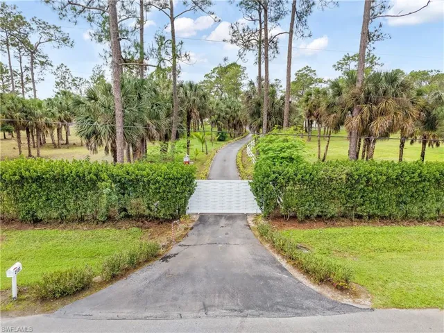 View of home's community featuring driveway, fence, a lawn, and a gate