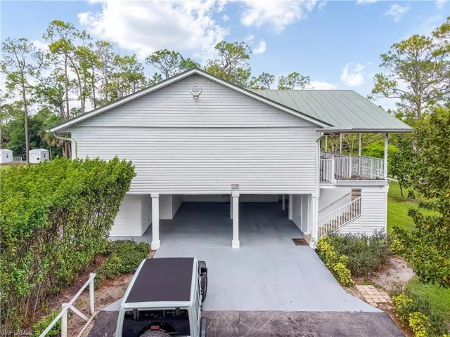 View of side of home featuring concrete driveway and a carport