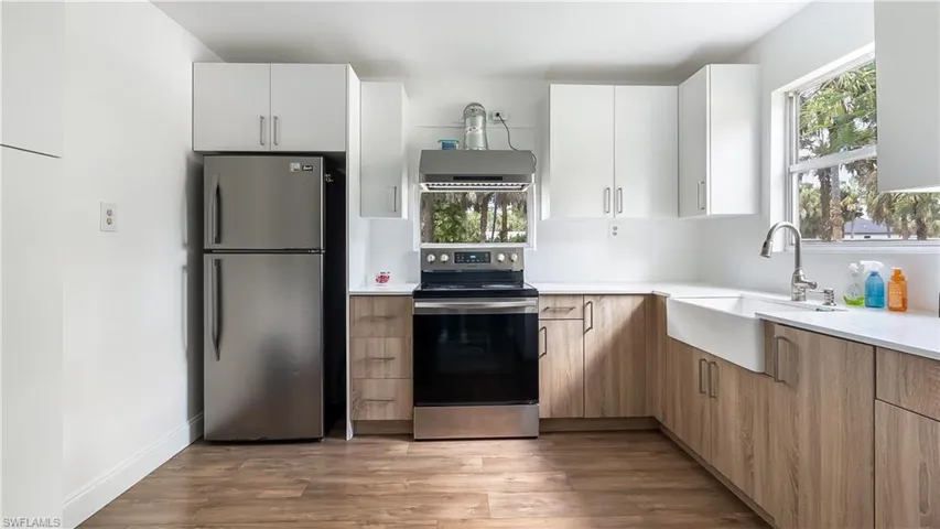 Kitchen with light wood-type flooring, light countertops, a sink, and appliances with stainless steel finishes