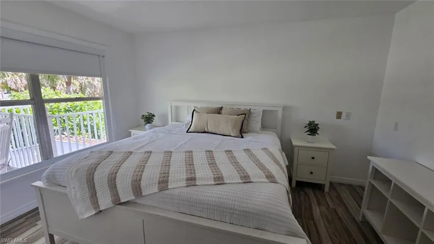 Bedroom with wood finished floors, baseboards, and multiple windows
