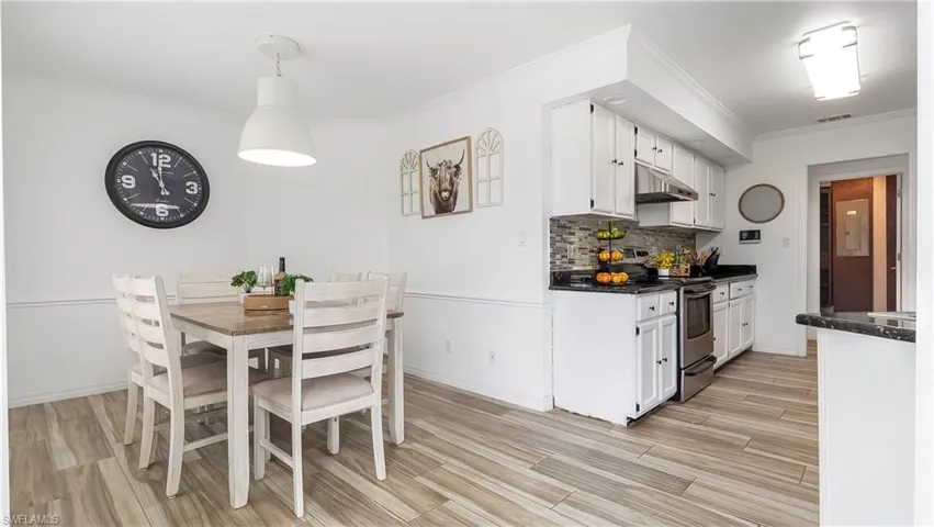 Dining area with baseboards, light wood-style flooring, visible vents, and crown molding