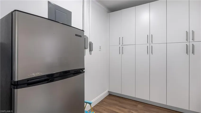 Kitchen featuring wood finished floors, freestanding refrigerator, and white cabinets