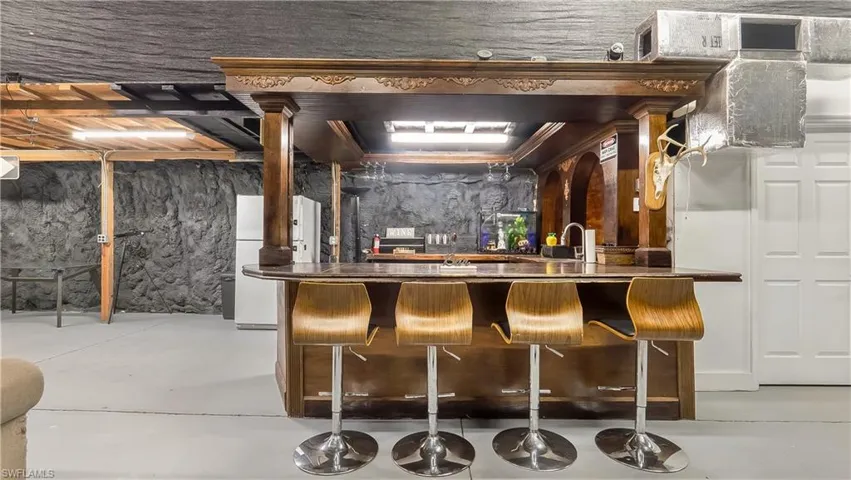 Bar featuring concrete floors, freestanding refrigerator, and a sink