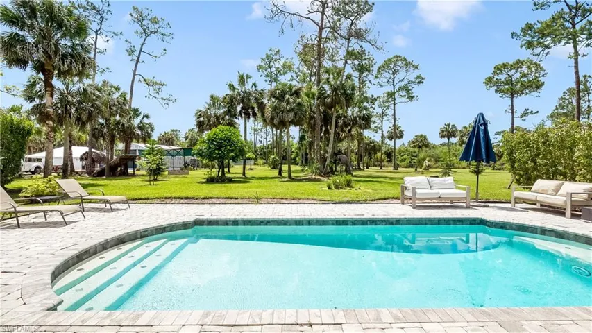 Pool with a patio area and a lawn