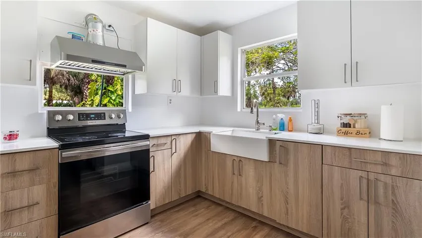 Kitchen featuring modern cabinets, a sink, light countertops, stainless steel electric range, and extractor fan