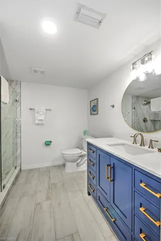 Bathroom featuring vanity, toilet, an enclosed shower, and wood-type flooring