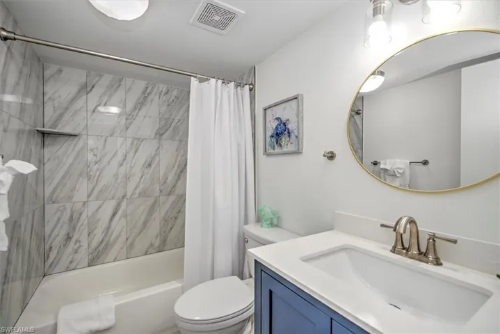 Full bathroom with toilet, vanity, and shower / tub combo with curtain