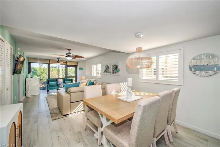 Dining space with ceiling fan with notable chandelier, a wealth of natural light, and light hardwood / wood-style flooring