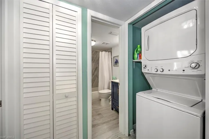 Clothes washing area featuring stacked washer / drying machine and light hardwood / wood-style floors