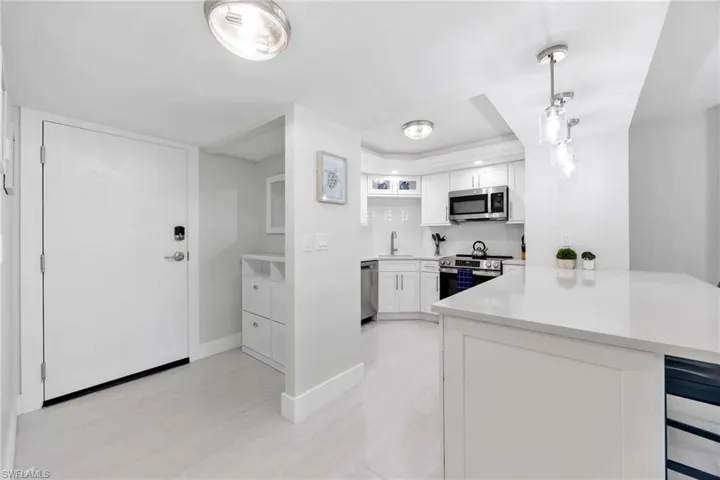 Kitchen featuring appliances with stainless steel finishes, a peninsula, a tray ceiling, light countertops, and white cabinetry