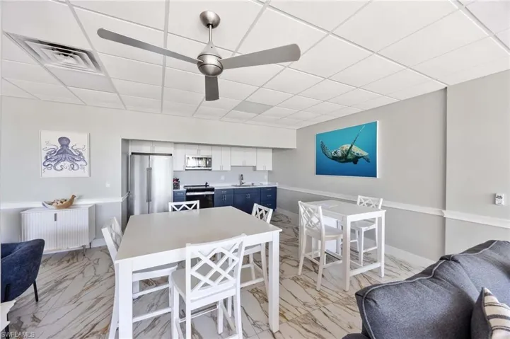 Dining room with radiator heating unit, light marble finish flooring, a drop ceiling, and ceiling fan