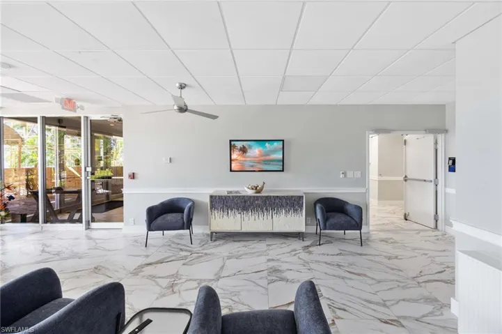 Living room with a drop ceiling, marble finish floors, and a ceiling fan