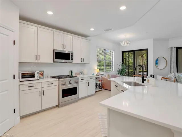 Kitchen with appliances with stainless steel finishes, a sink, light countertops, tasteful backsplash, and crown molding