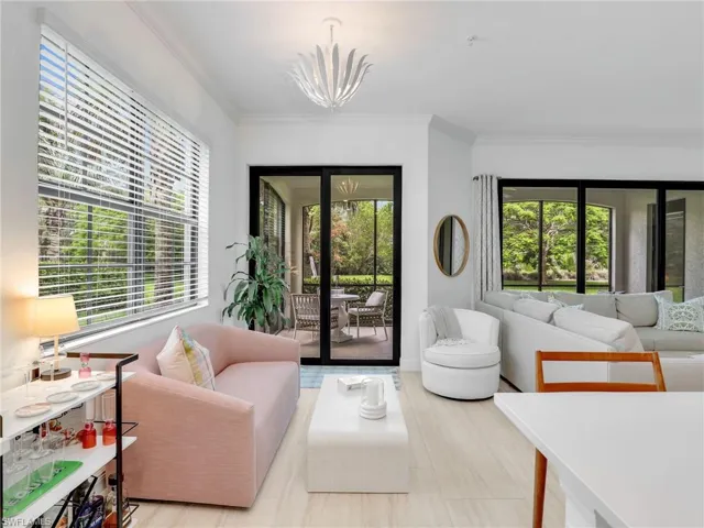 Living area with healthy amount of natural light, crown molding, a chandelier, and baseboards