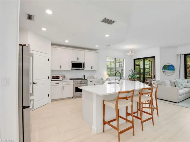 Kitchen featuring appliances with stainless steel finishes, a sink, open floor plan, light countertops, and white cabinetry