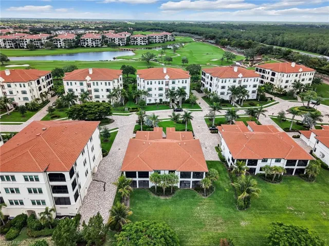 Aerial view of a golf course, a nearby body of water, and apartment complex / building