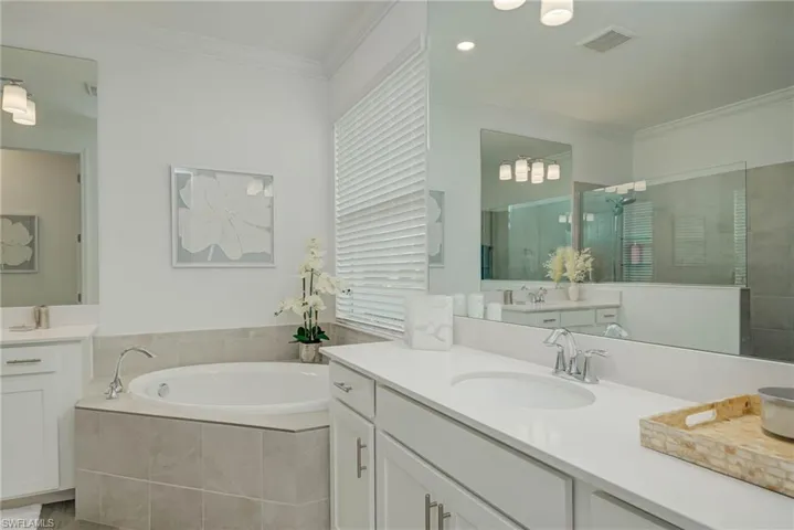 Master Bathroom with garden soaking tub, double vanities, shower stall, crown molding