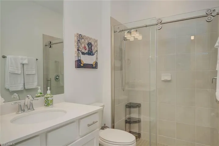 Bathroom with quartz vanity and walk-in shower with custom glass door