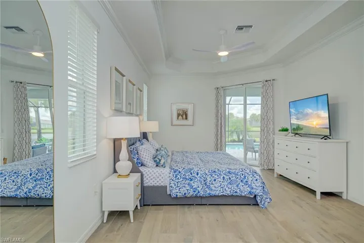 Master Bedroom with light wood-style flooring, access to exterior, crown molding, ceiling fan, and a tray ceiling