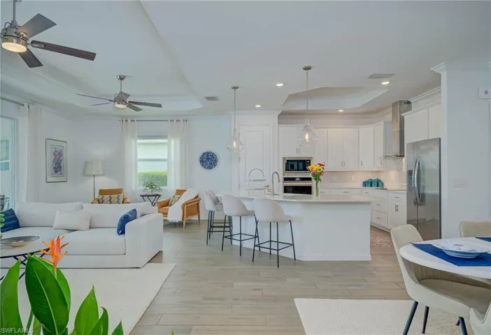 Great room with a tray ceiling, crown molding, light wood-style floors, recessed lighting, and a ceiling fans and Chef's Kitchen with seating at Quartz Countertop
