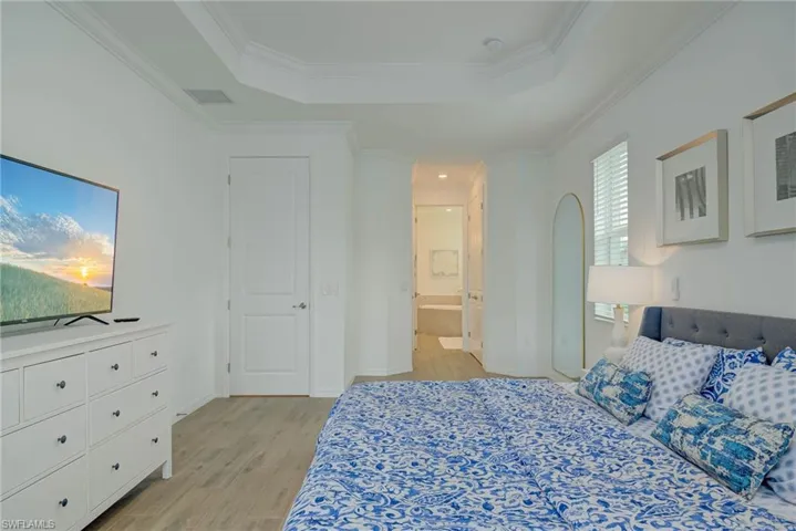 Master Bedroom w/walk-in closet (His & Hers) with light wood-style floors, connected bathroom, a tray ceiling, and crown molding