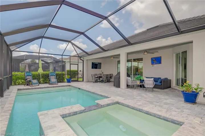 View of pool with covered outdoor lounge area with pavers, double ceiling fans, and a Beautiful heated pool with spacious hot tub