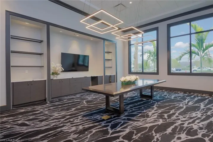 Community Gathering Room in 24,000 sq ft clubhouse with TV, built in shelves and a chandelier