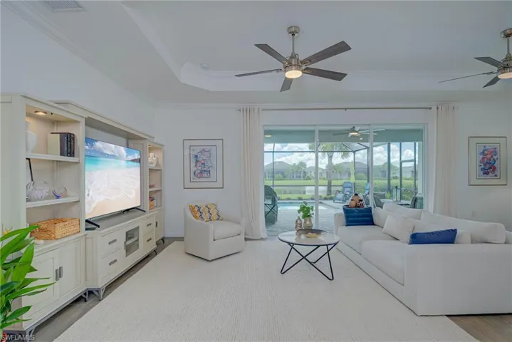 Great room with crown molding, a coffered ceiling, light wood-style tile flooring & decorative ceiling fans