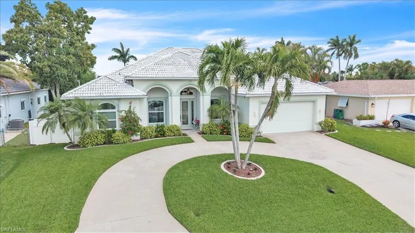 Mediterranean / spanish-style house with stucco siding, curved driveway, a front yard, a concrete tiled roof, and a garage