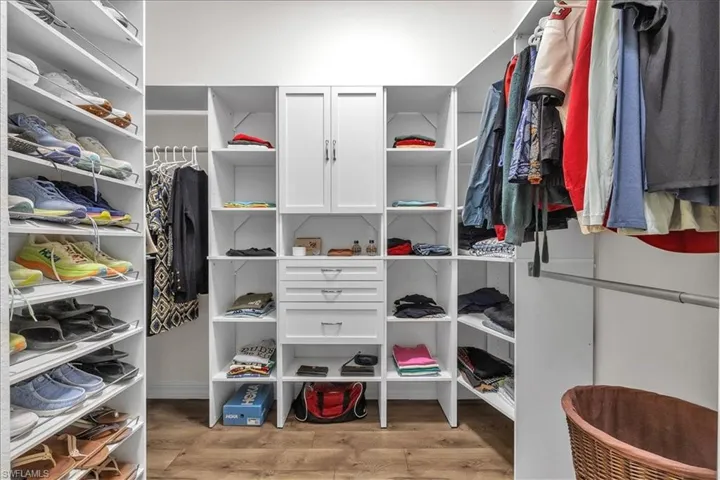 Master Walk in closet with light wood-style laminate flooring