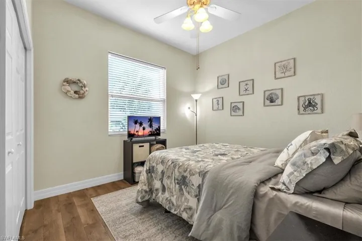 Guest Bedroom featuring dark wood-like laminate flooring, a closet, and a ceiling fan