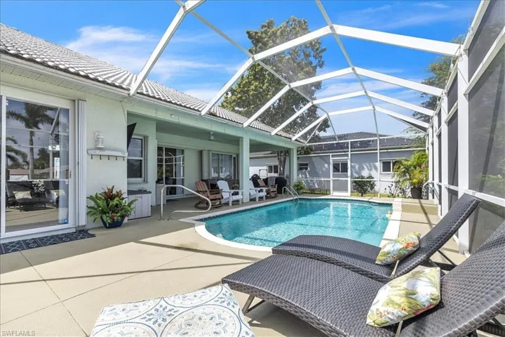 Swimming pool with a lanai, a patio, and a grill