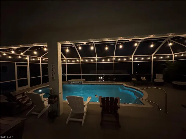 Pool at night featuring an outdoor pool, a patio area, and a lanai
