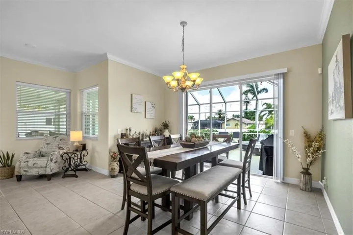 Dining area featuring hanging lights, light tile patterned flooring, ornamental molding, and plenty of natural light