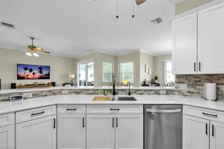 Kitchen featuring ceiling fan, dishwasher, white cabinetry, soft close drawers  backsplash, and ornamental molding