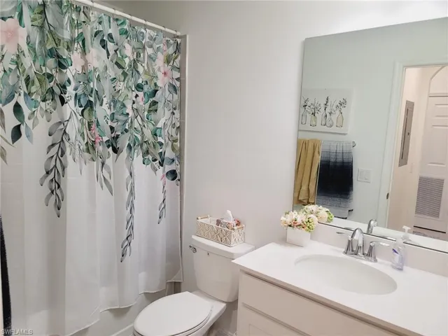 Bathroom with vanity, a shower with shower curtain, and toilet