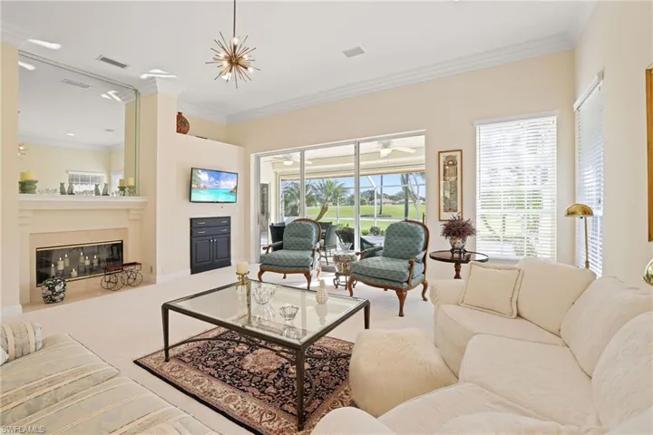 Carpeted living room with ornamental molding and an inviting chandelier