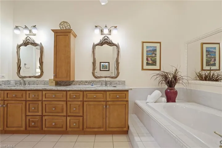 Bathroom featuring vanity, tiled tub, and tile patterned floors