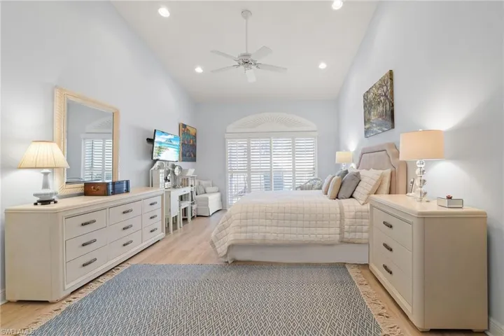 Bedroom featuring ceiling fan, high vaulted ceiling, multiple windows, and light hardwood / wood-style flooring