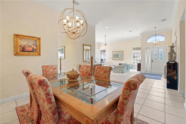 Dining room featuring an inviting chandelier, light tile patterned floors, and ornamental molding