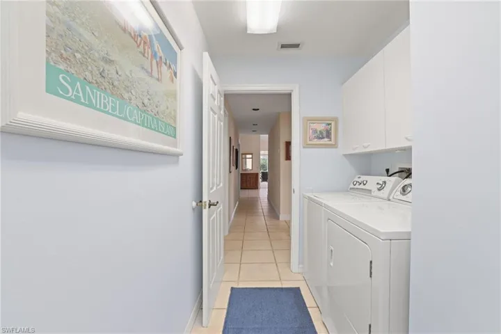 Washroom with separate washer and dryer, cabinets, and light tile patterned flooring