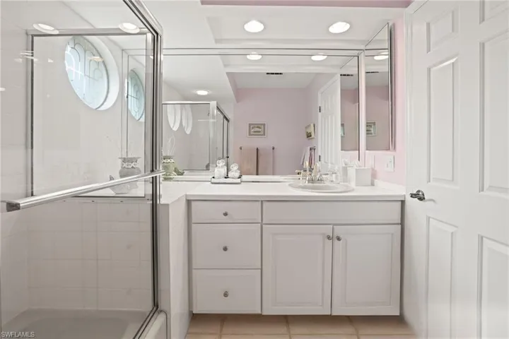 Bathroom with walk in shower, vanity, and tile patterned flooring