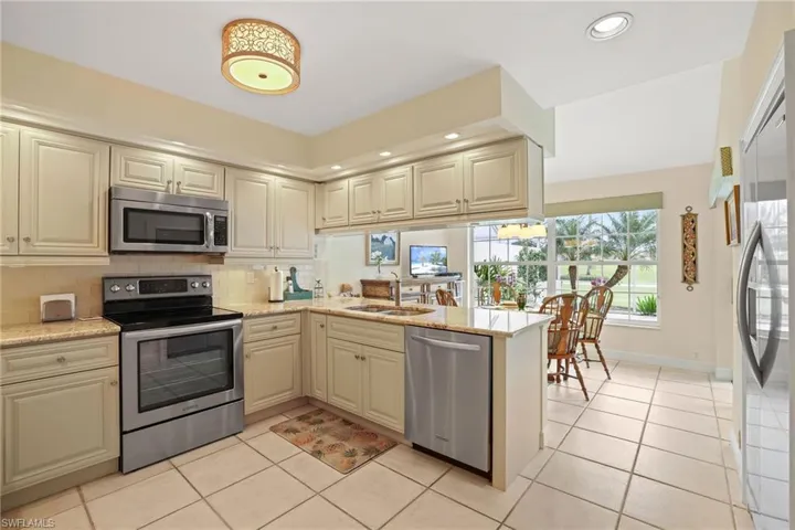 Kitchen featuring appliances with stainless steel finishes, tasteful backsplash, sink, kitchen peninsula, and cream cabinetry