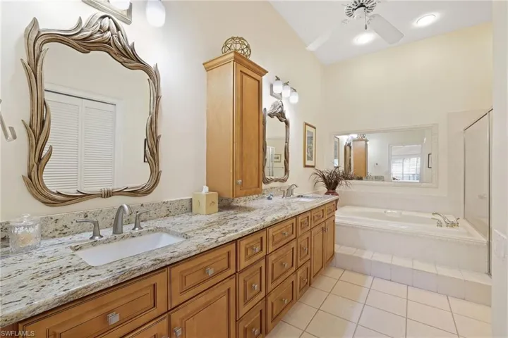 Bathroom featuring vanity, a relaxing tiled tub, tile patterned floors, and ceiling fan