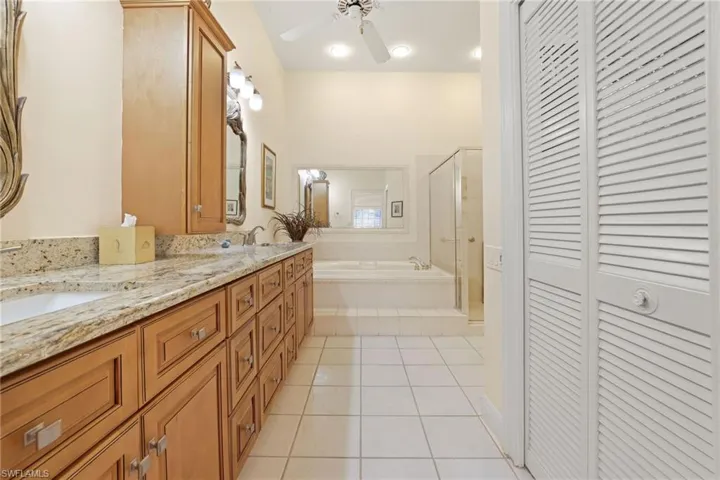Bathroom with ceiling fan, tile patterned floors, separate shower and tub, and vanity